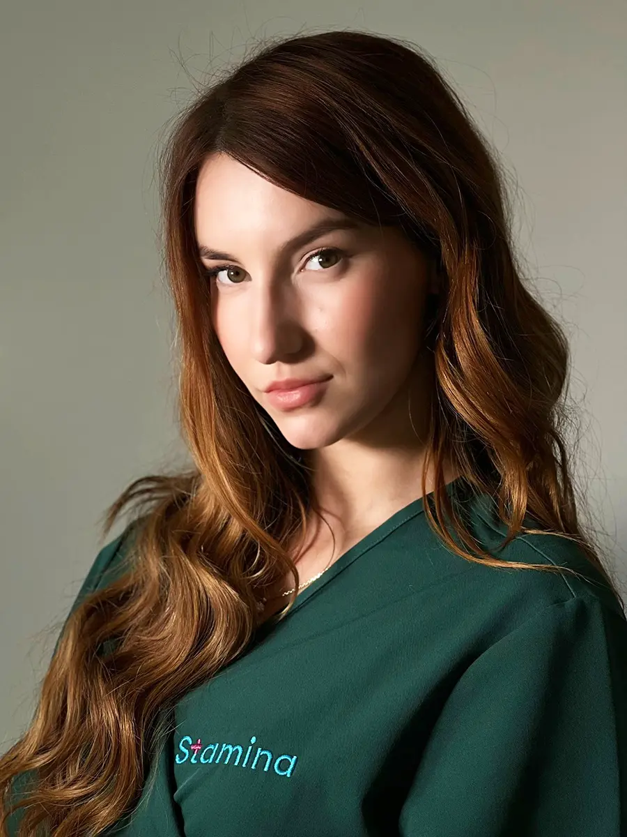 Portret mgr Wiktorii Trybus, psychologa w Centrum Stamina w Gliwicach, ubrana w zielony fartuch medyczny z widocznym logo "Stamina".